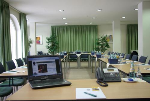 una sala conferenze con tavoli, computer portatile e telefono di Hotel Goldener Anker a Radebeul