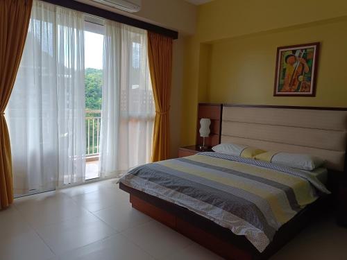 a bedroom with a bed and a large window at Miranda 514B 2br at Pico de Loro by Raquel's Place in Nasugbu