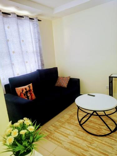 a living room with a black couch and a table at Cozy One bedroom B&B in Thika