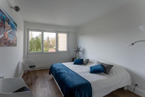 a bedroom with a bed with blue sheets and a window at Appartement de luxe, St Germain en Laye, Neuf in Saint-Germain-en-Laye