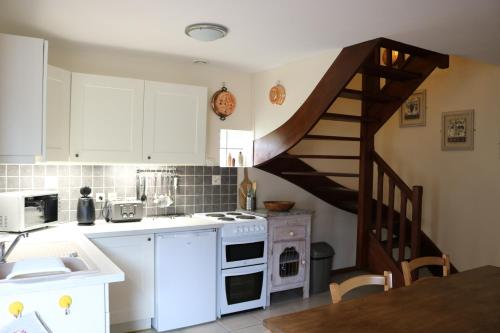 une cuisine avec des placards blancs et un escalier en colimaçon dans l'établissement Auberge des Chevaliers, à Canlers