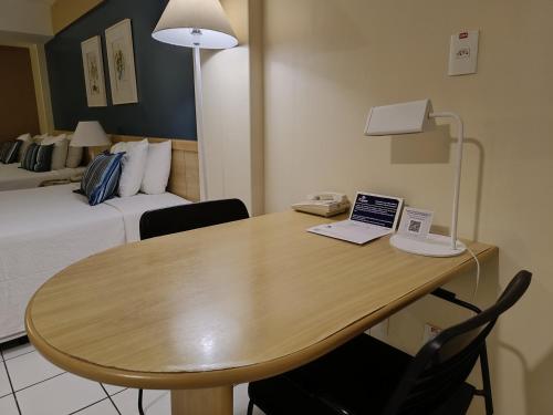 a room with a table with a laptop and a bed at Reymar Hotel Maceió in Maceió