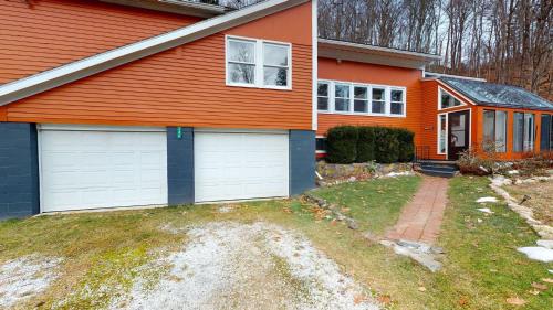 an orange house with white garage doors in a yard at Winter Lore Brought to you by GetAway Vacations in Mendon