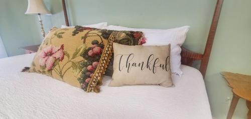 a bed with pillows with a thankful sign on it at Old Orchard House Brought to you by GetAway Vacations in Brandon