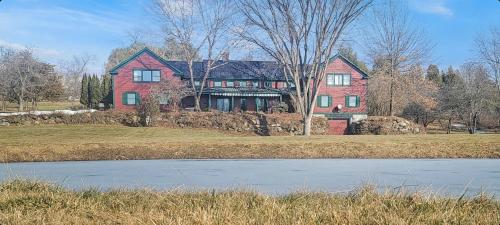 a large red house with a pond in front of it at Old Orchard House Brought to you by GetAway Vacations in Brandon