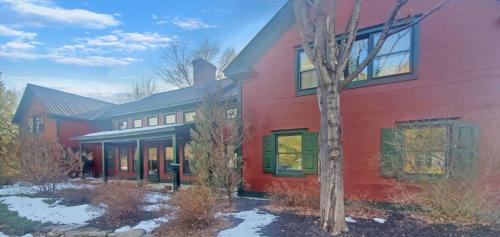 a red house with a tree in front of it at Old Orchard House Brought to you by GetAway Vacations in Brandon