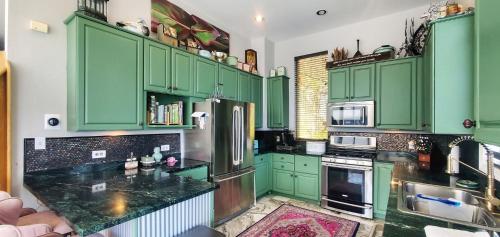 een keuken met groene kasten en zwarte aanrechtbladen bij Marble House home in Bomoseen
