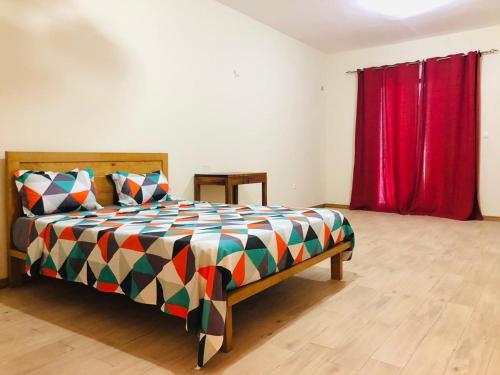 1 dormitorio con cama y cortina roja en Get house kira, en Cidade Velha