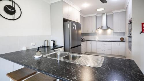 a kitchen with white cabinets and a black counter top at Take A Dip At Eucalypt in Bellara