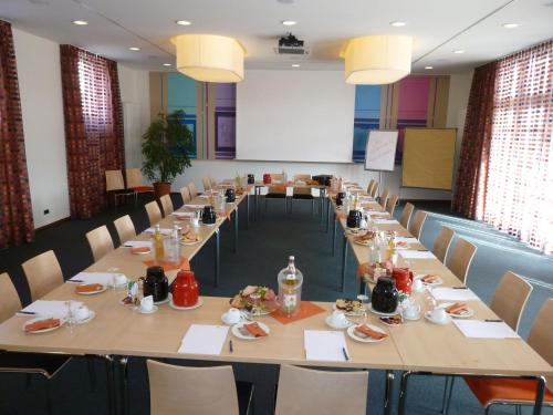 a meeting room with long tables and chairs at Hotel Klostergarten in Kevelaer