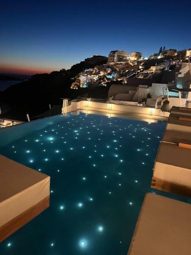 a pool with lights in the water at night at La Perla Villas and Suites - Adults Only in Oia