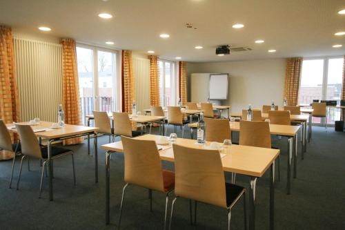 a classroom with tables and chairs in a room with windows at Hotel Klostergarten in Kevelaer