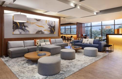 una sala de estar con sofás, mesas y sillas en Fairfield by Marriott Bogota Embajada en Bogotá