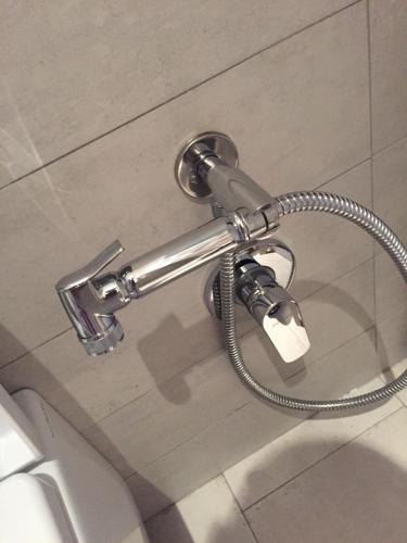 a hose hooked up to a toilet in a bathroom at Heda House in Sanyang