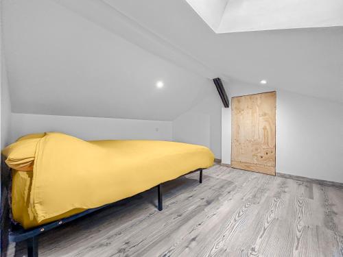 een geel bed in een kamer met een houten vloer bij Écrin du Centre Ville Stéphanois in Saint-Étienne