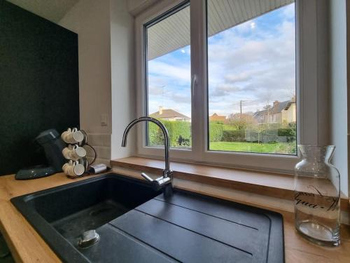 a kitchen with a sink and a large window at La Tanière de la baie - Maison 6-8 pers in Le Val-Saint-Père