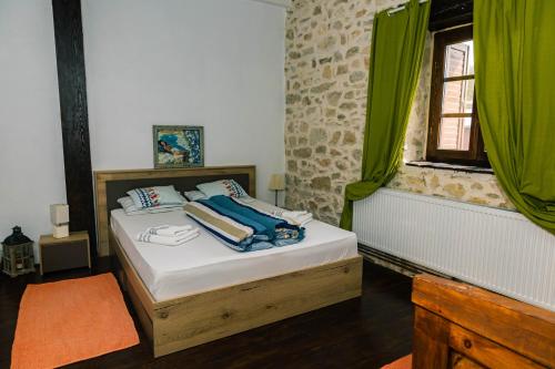a bedroom with a bed with green curtains and a window at Casa Thea Cheile Nerei in Socolari
