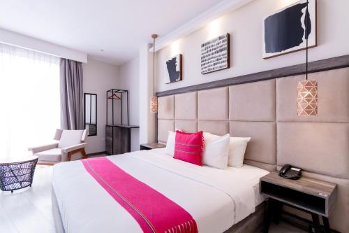 een hotelkamer met een groot bed met roze kussens bij Arkana Grupo Amber - Collection O in Puebla