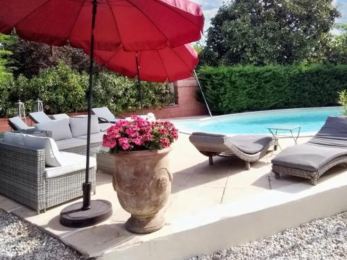 eine Terrasse mit einem roten Sonnenschirm und einem Pool in der Unterkunft Villa de 3 chambres avec piscine privee jardin clos et wifi a Arsac in Arsac