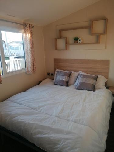 a bedroom with a large white bed with a window at 4-Bedroom Caravan static home in Clacton-on-Sea in Clacton-on-Sea