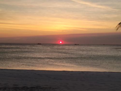 a sunset on the beach with the sun in the horizon at Friend of Nature Bungalow in Koh Rong Island