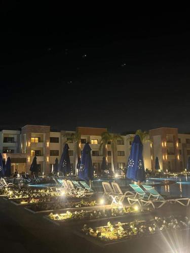 a group of chairs and umbrellas at a resort at night at شقه فندقيه - هلنان بورفؤاد in Port Said