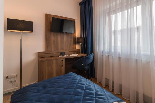 a hotel room with a bed and a desk and a television at Hotel am Brauerei-Dreieck in Bamberg