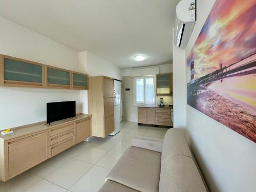 uma sala de estar com um sofá e uma televisão de ecrã plano em Appartamento Al Faro I TerraceRelax&Parking em Lignano Sabbiadoro