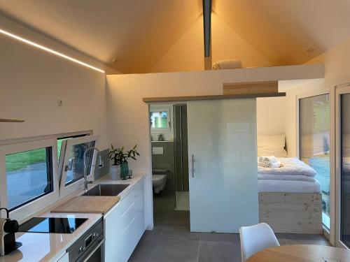 eine Küche mit einem Waschbecken und ein Bett in einem Zimmer in der Unterkunft Tinyhaus Supreme für 1-4 Personen in Fuchsmühl