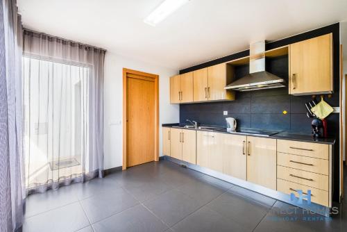 a kitchen with wooden cabinets and a sink and a window at Villas Rocha in Albufeira