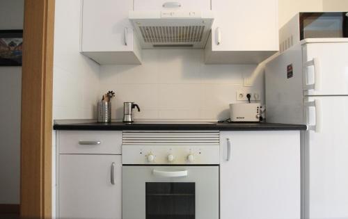 La cuisine est équipée de placards blancs et d'un four avec plaques de cuisson. dans l'établissement Apartamento Labegain 3, à Sestao