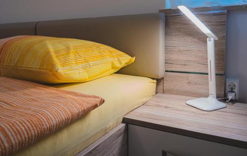 a bed with a yellow pillow and a lamp at Apartma Ksenija in Črniče