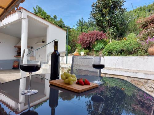 a table with two glasses of wine and fruit on it at Casa Rio Zêzere in Pedrógão Pequeno