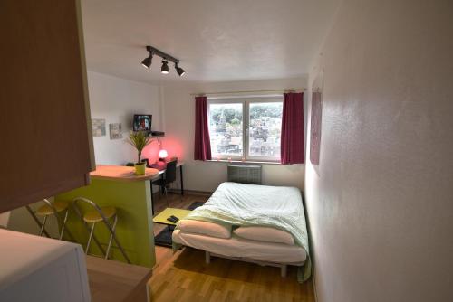 リエージュにあるQuai De Romeのベッドとデスクが備わる小さな客室です。
