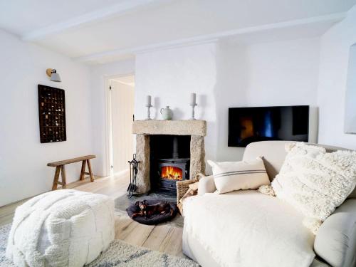 a living room with a white couch and a fireplace at Bell Cottage in Saint Teath