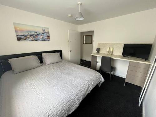 a bedroom with a bed and a desk with a television at The M Rooms in Kirk of Shotts