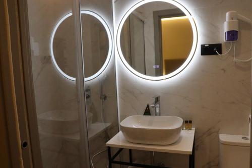 a bathroom with a sink and a shower with two mirrors at Hostal La Rúa-Montera in Madrid