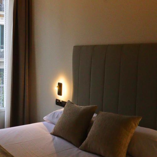 a bedroom with a bed with a headboard and a light at Hostal La Rúa-Montera in Madrid