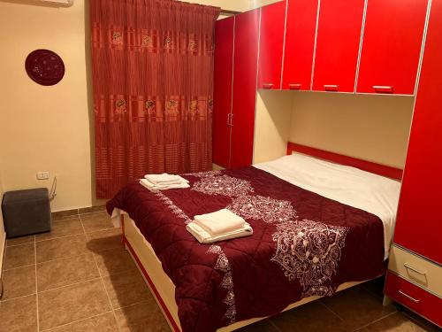 um quarto com armários vermelhos e uma cama com toalhas em Anisa appartament em Durrës