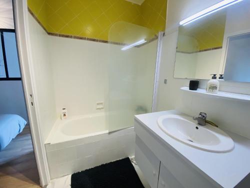 uma casa de banho branca com um lavatório e uma banheira em Le Soulicou em Rodez