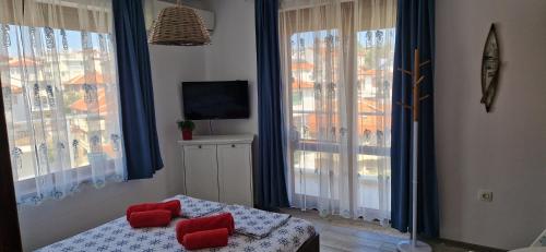 a bedroom with a bed with red pillows and windows at Apartment Turquoise Sozopol in Sozopol