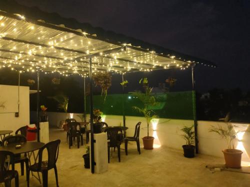 d'une terrasse avec des tables et des chaises sous un auvent éclairé. dans l'établissement LE TOWNSHIP RESIDENCY, à Pondichéry