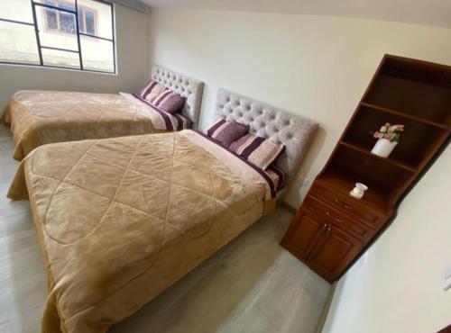 ein Schlafzimmer mit 2 Betten und einer Kommode darin in der Unterkunft Departamento Enorme en Condominio Privado del Centro Histórico. Ecualodge 29 in Cuenca