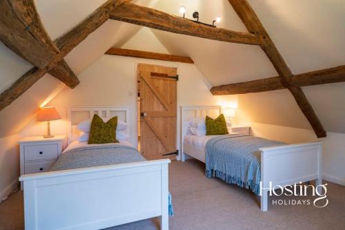 2 łóżka w sypialni na poddaszu z drewnianymi belkami stropowymi w obiekcie Bullocks Farm House - 6 Exceptional Bedrooms w mieście High Wycombe