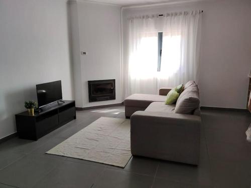 een woonkamer met een bank en een tv bij Casa da Esteva - Vila de Rei in Vila de Rei