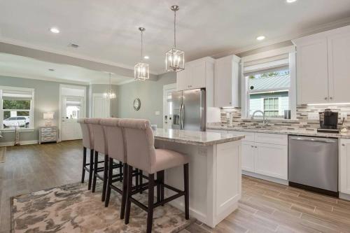 a kitchen with white cabinets and a island with bar chairs at *Chic Beach Cottage Retreat* near Beach/downtown in Gulfport