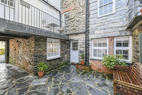 a brick house with a white door and a bench at Old Cobblers in Port Isaac