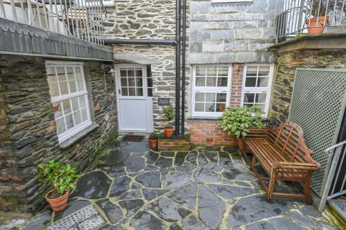 a stone house with a bench and windows at Old Cobblers in Port Isaac