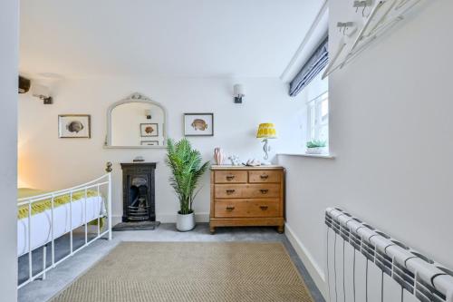 a room with white walls and a dresser with a fireplace at Old Cobblers in Port Isaac