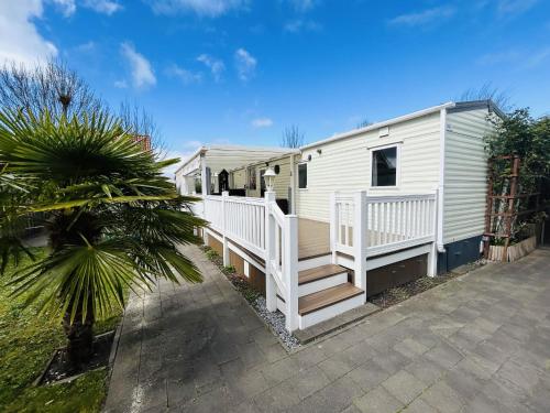 a white mobile home with a porch and a staircase at Beach Resort Nieuwvliet Bad - NV 102 in Nieuwvliet